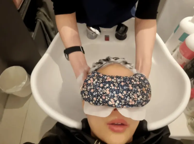 컬러룸 이충점 샴푸대에서 눈에 아이패치를 하고 두피 관리를 받는 장면